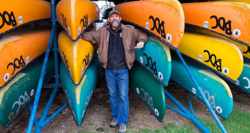 Secretary Mike Mills, surrounded by canoes.