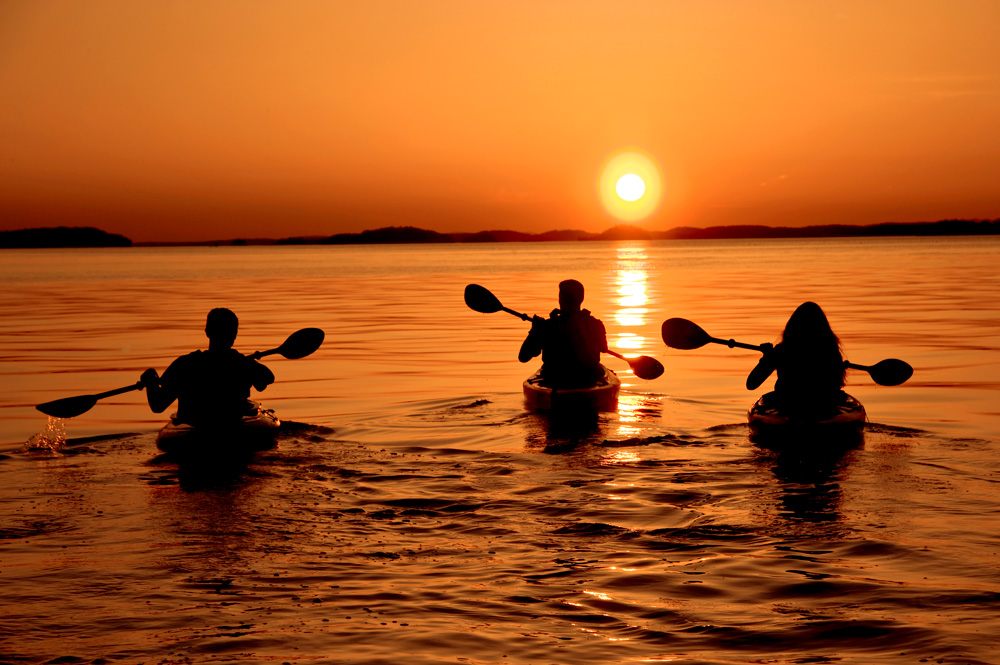 Kayakers paddling into the sunset on Lake Ouachita