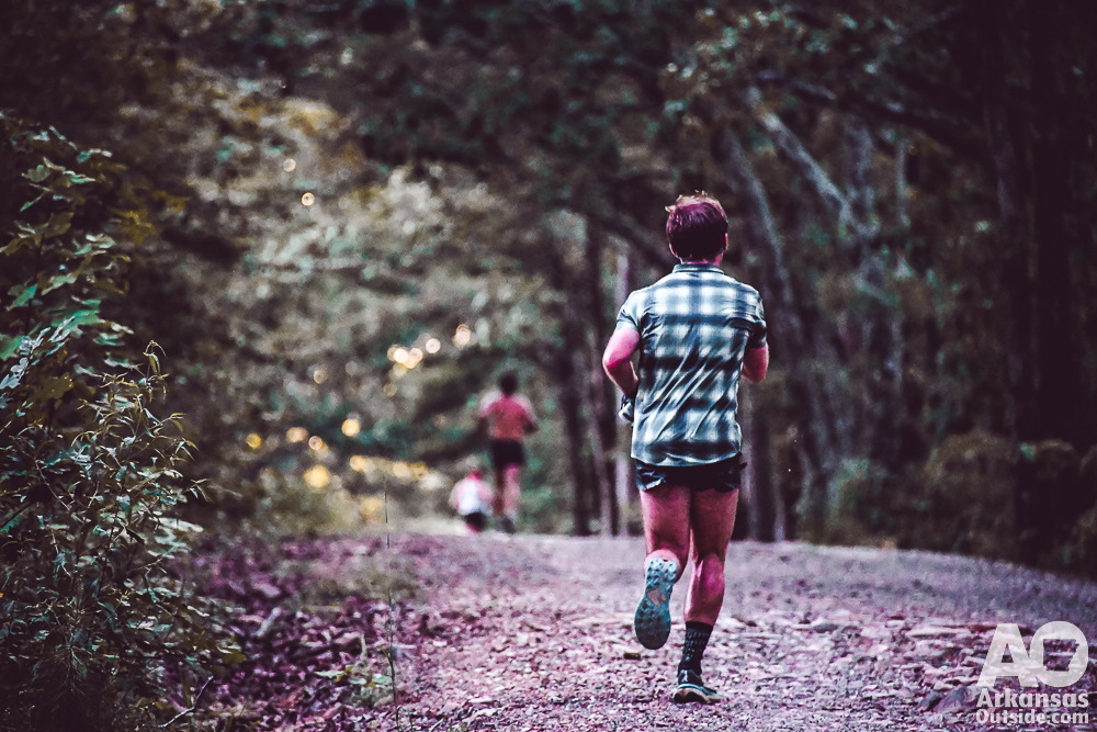 A single runner heading up a gravel road after leaving an aid station.