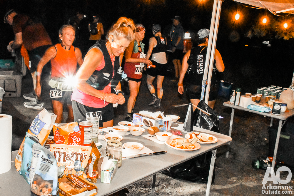 Runners moving about the aid station picking up some refreshments, hydration, and encouragement.