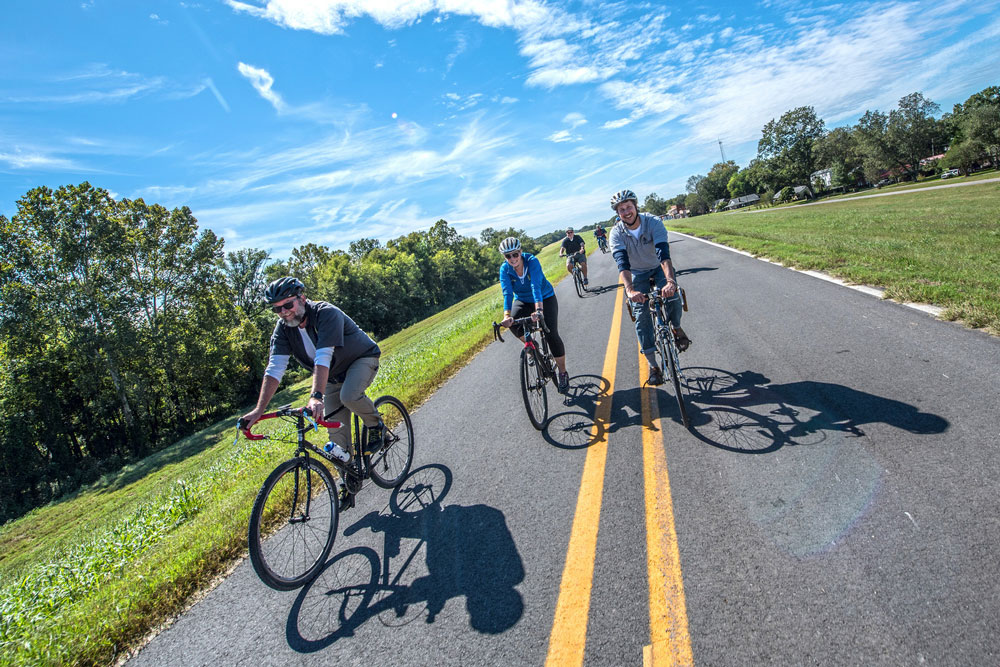 Bicycle Riders on a paved trail atop a levee near the Arkansas River.