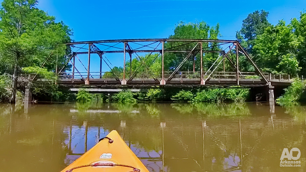 A kayak approaching a historic bridge on a river.