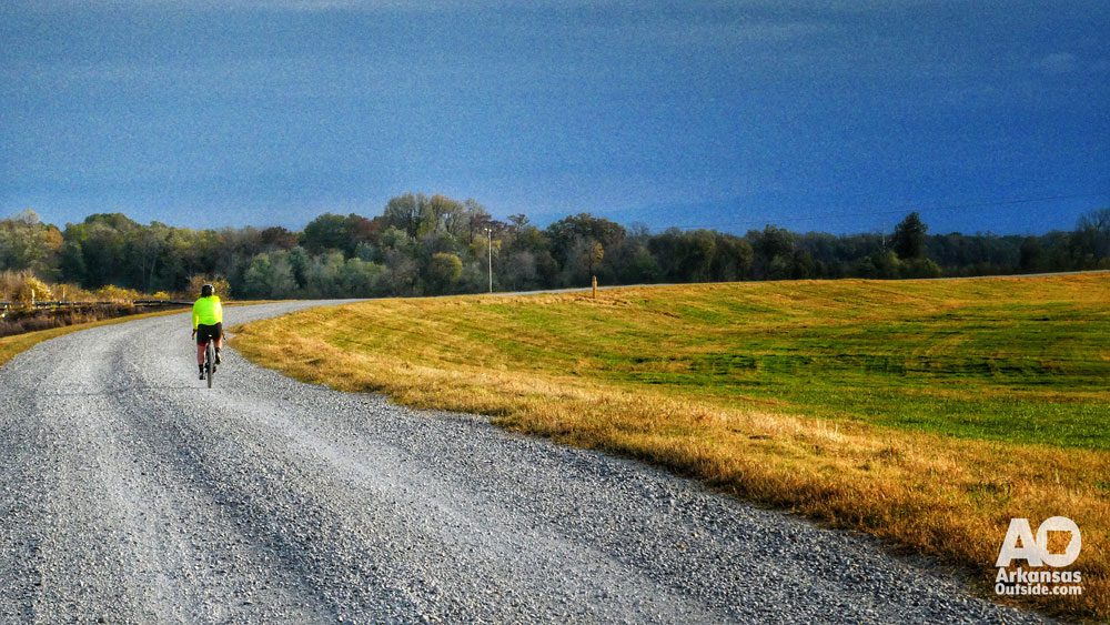 Solitary bicyclist riding a gravel road through the Arkansas Delta as sunset approaches. Ozark Foundation Rural Recreational Roads program