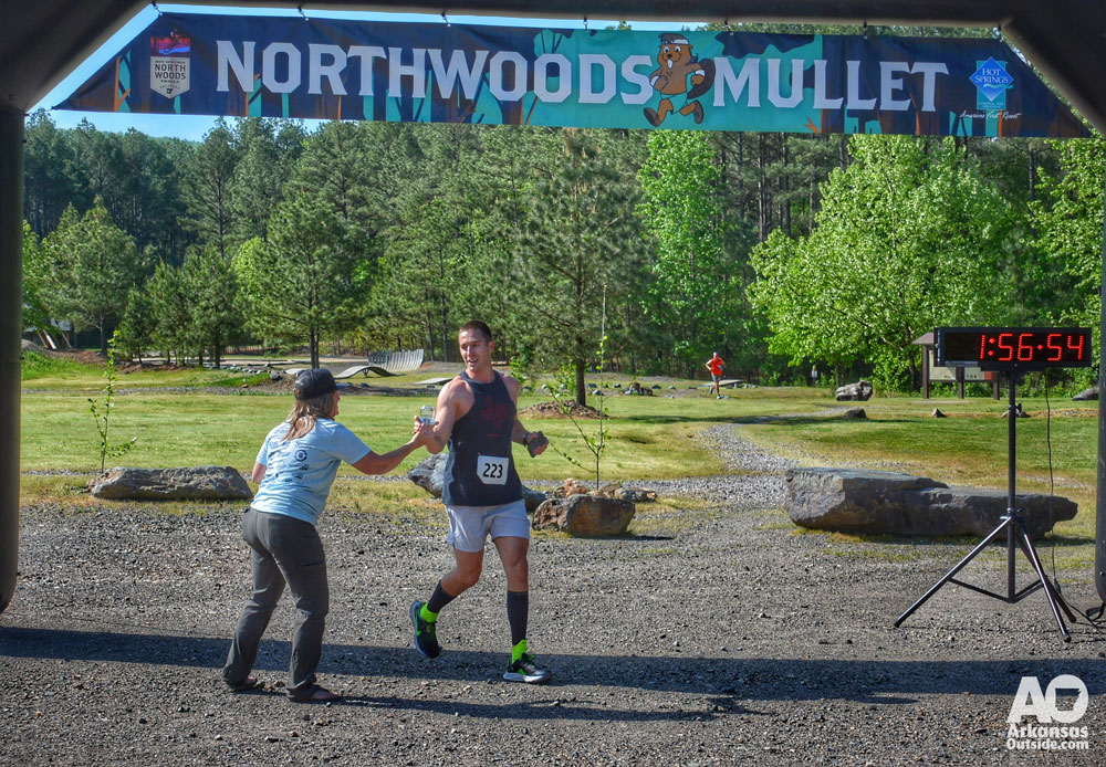 Runner crossing the finish line at the Northwoods Mullet Trail Run Hot Springs Arkansas