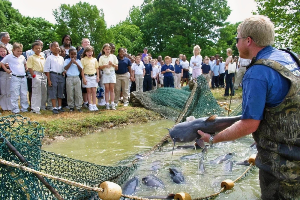 AGFC Assistant Chief of Fisheries Jason Miller shows a school group how catfish are harvested from ponds to be stocked around the state. AGFC photo. 
